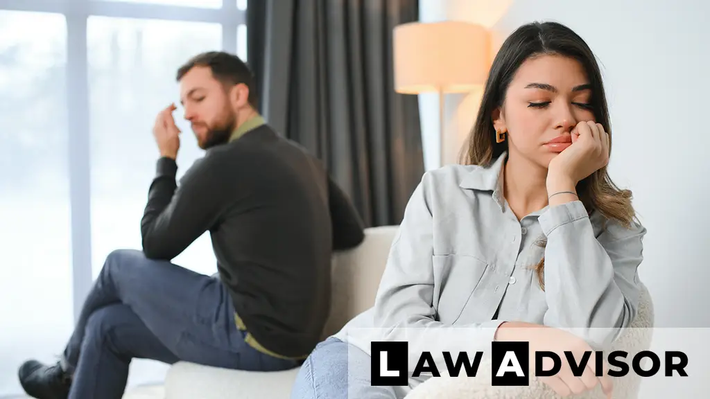 Unhappy couple sitting back-to-back on a couch, symbolizing conflict and emotional stress during a divorce process.