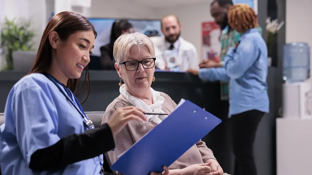 Asian nurse speaking with an elderly patient, symbolizing healthcare billing explanations and patient support.
